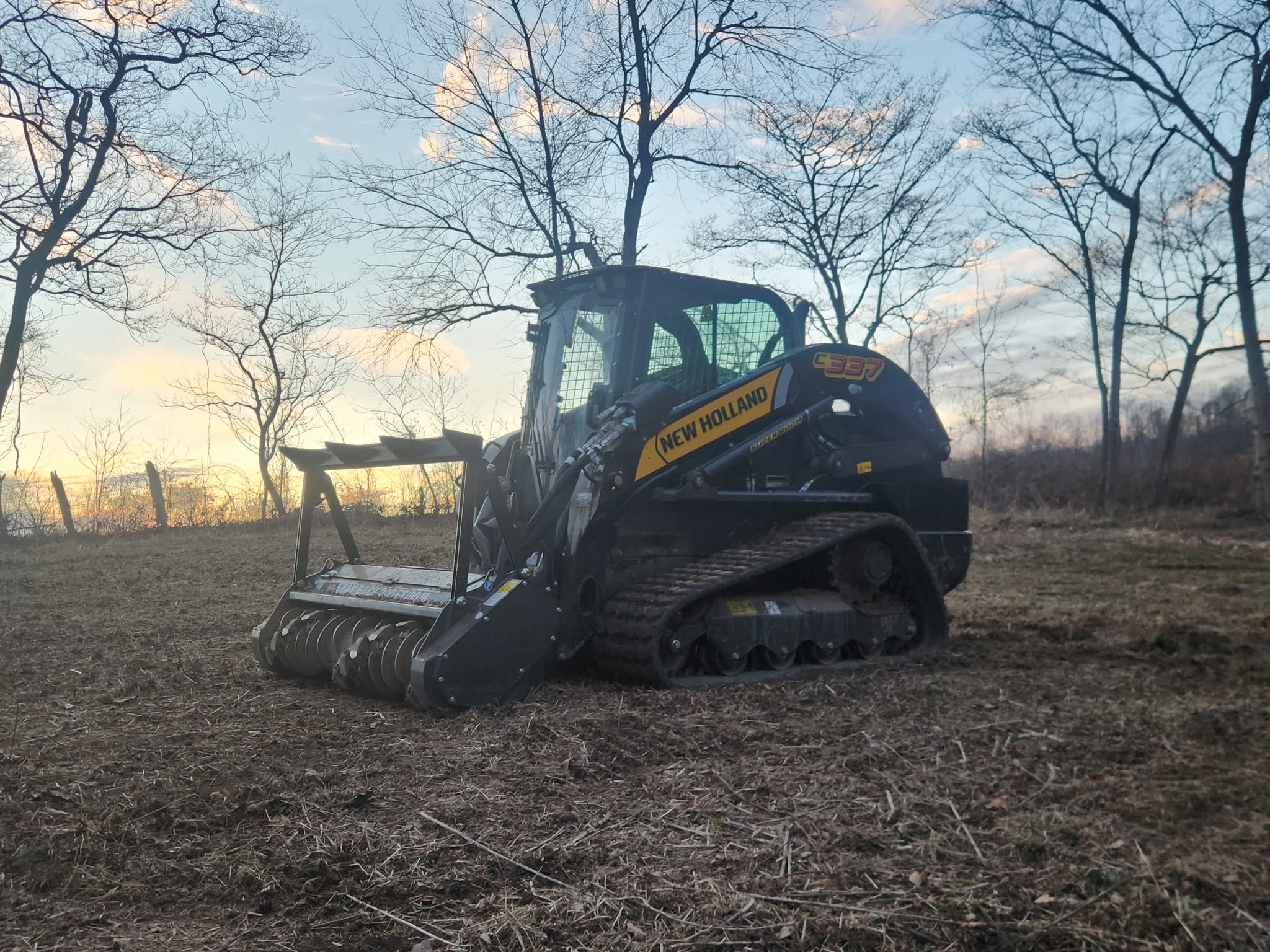 BlueGrid's New Holland C337 track loader with its mulching head, working at dusk